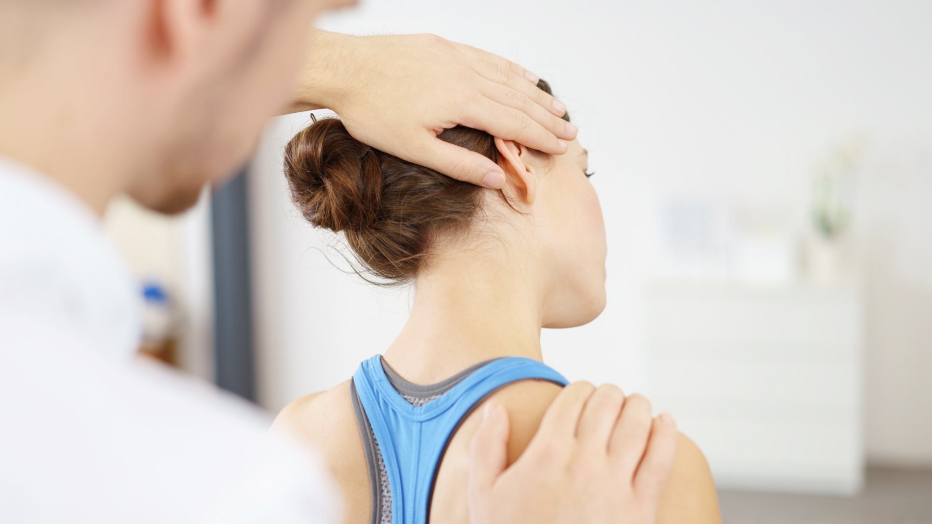 Physiotherapeut korrigiert den Nacken einer jungen Frau aufgrund einer Fehlstellung durch falsches Kissen